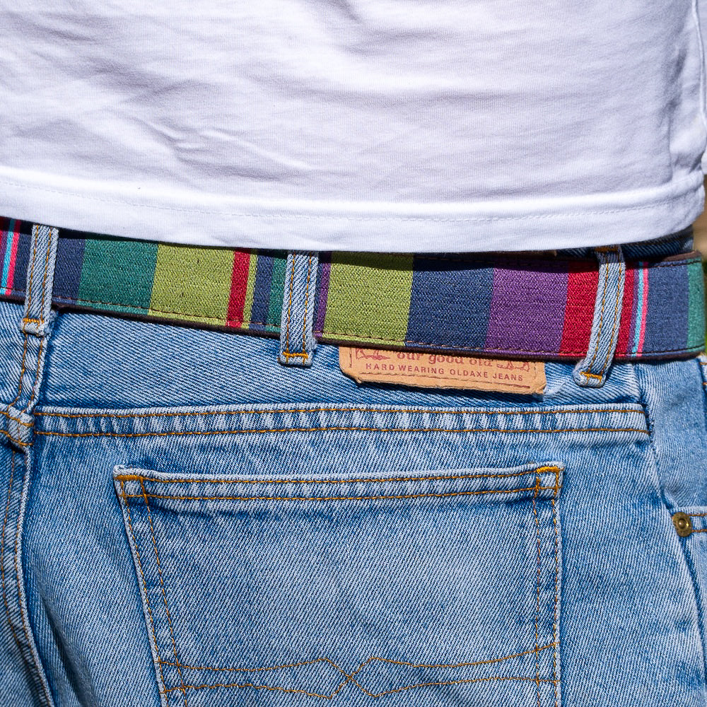 Close-up of a person wearing blue jeans with a colorful belt