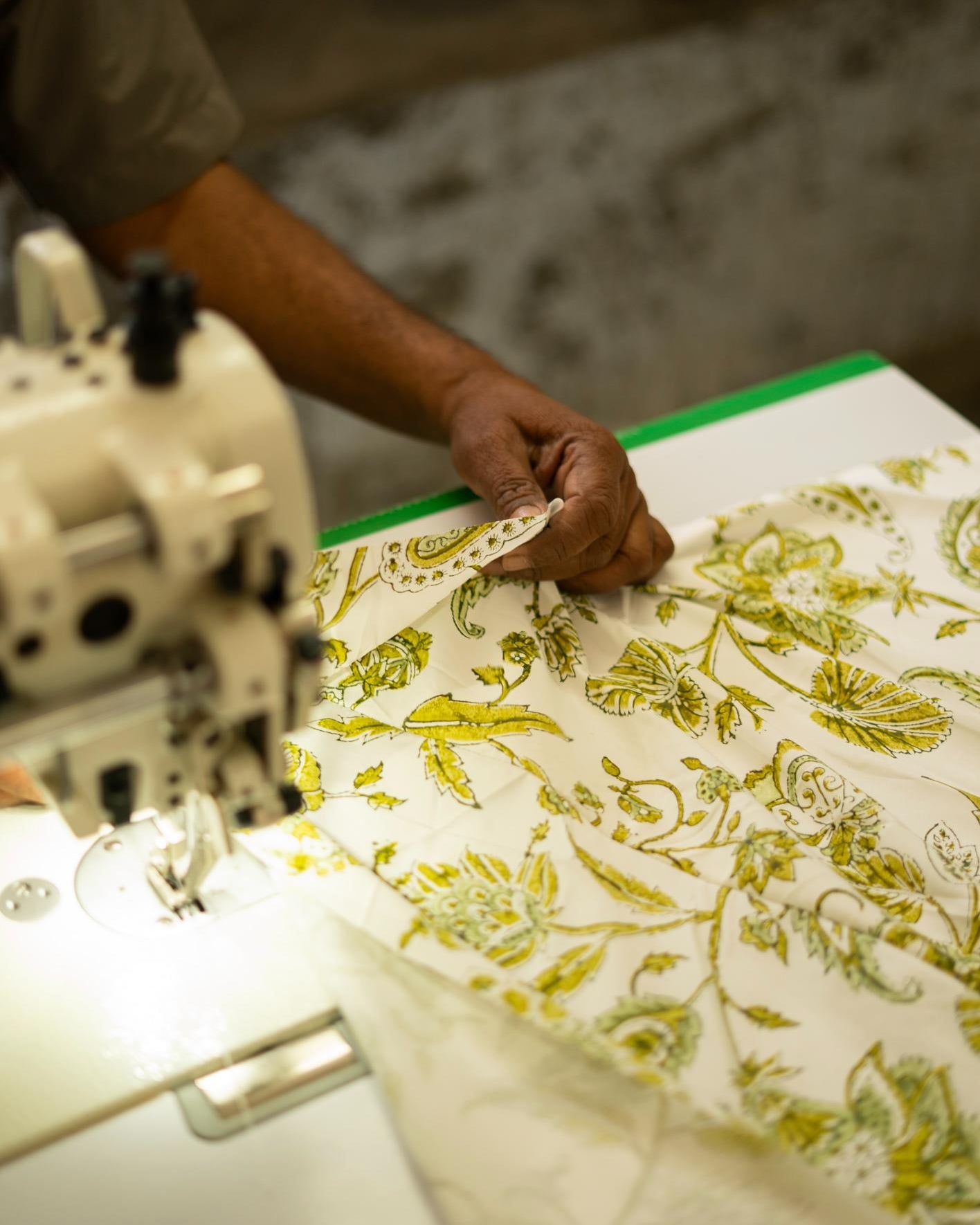 Person working with fabric and a sewing machine on a table.