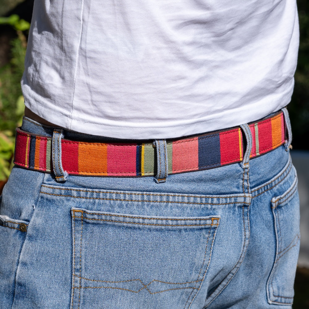 Person wearing a colorful striped belt with blue jeans outdoors