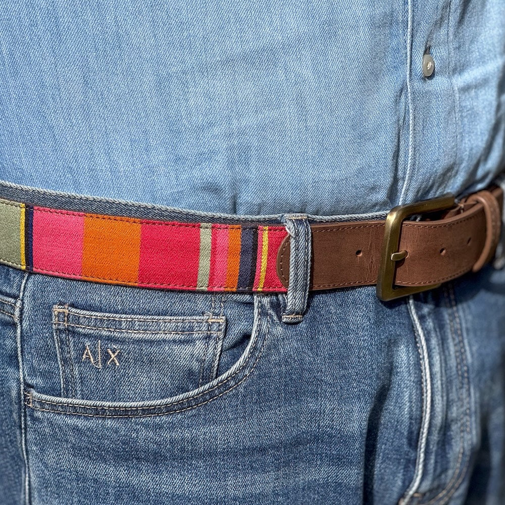 Close-up of a person wearing blue jeans with a colorful belt