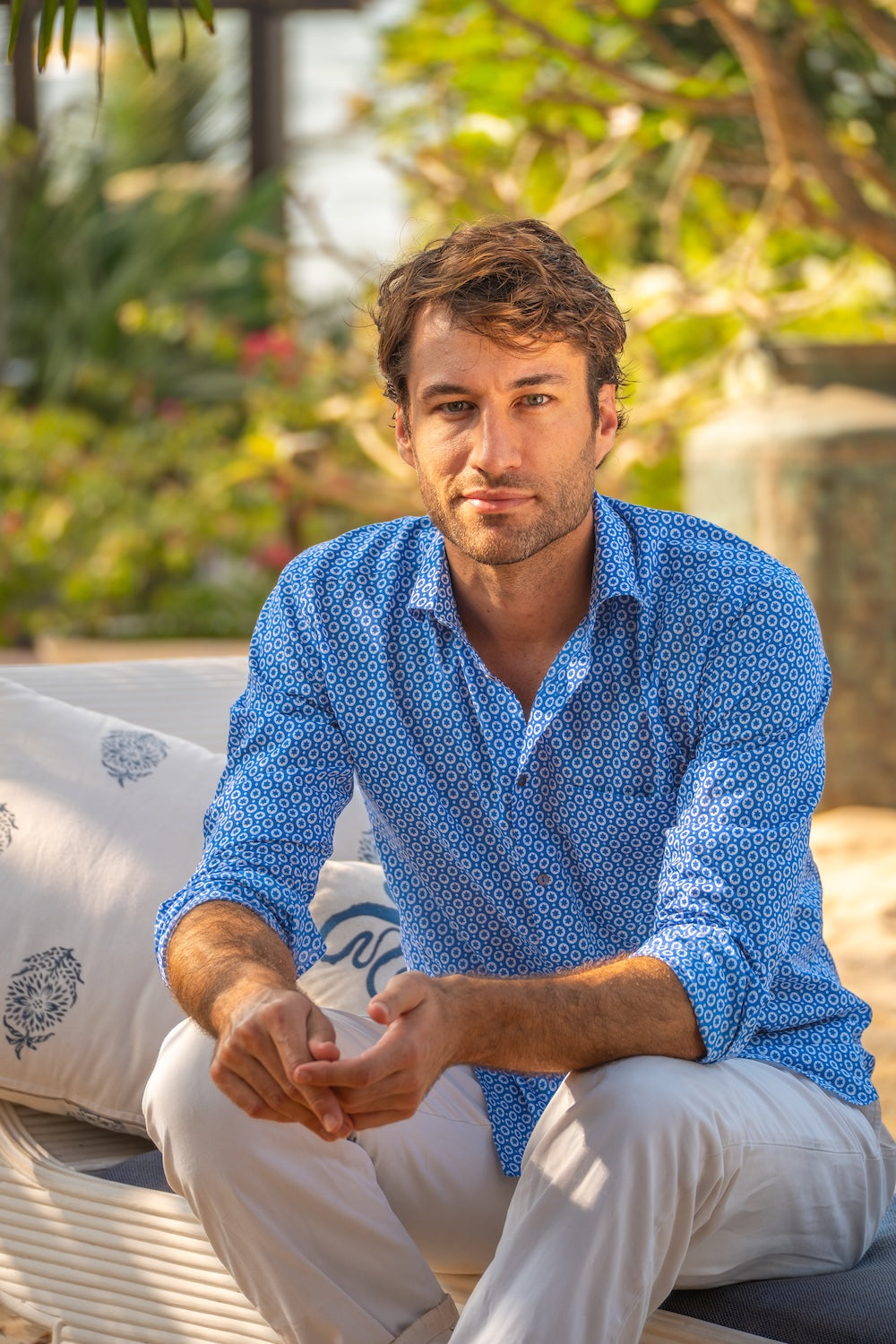Man wearing a blue patterned shirt sitting outdoors