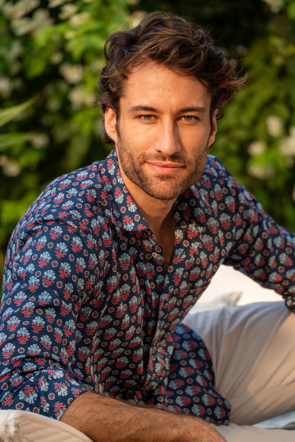 Man wearing a patterned shirt sitting outdoors